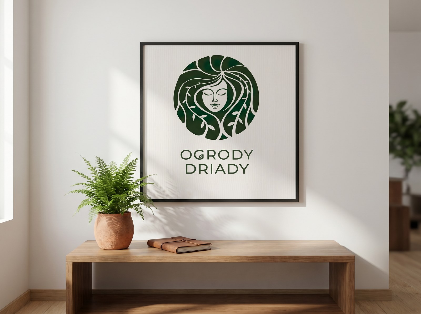 Hero pracowni — oprawiony plakat z logiem Ogrody Driady w jasnym wnętrzu.